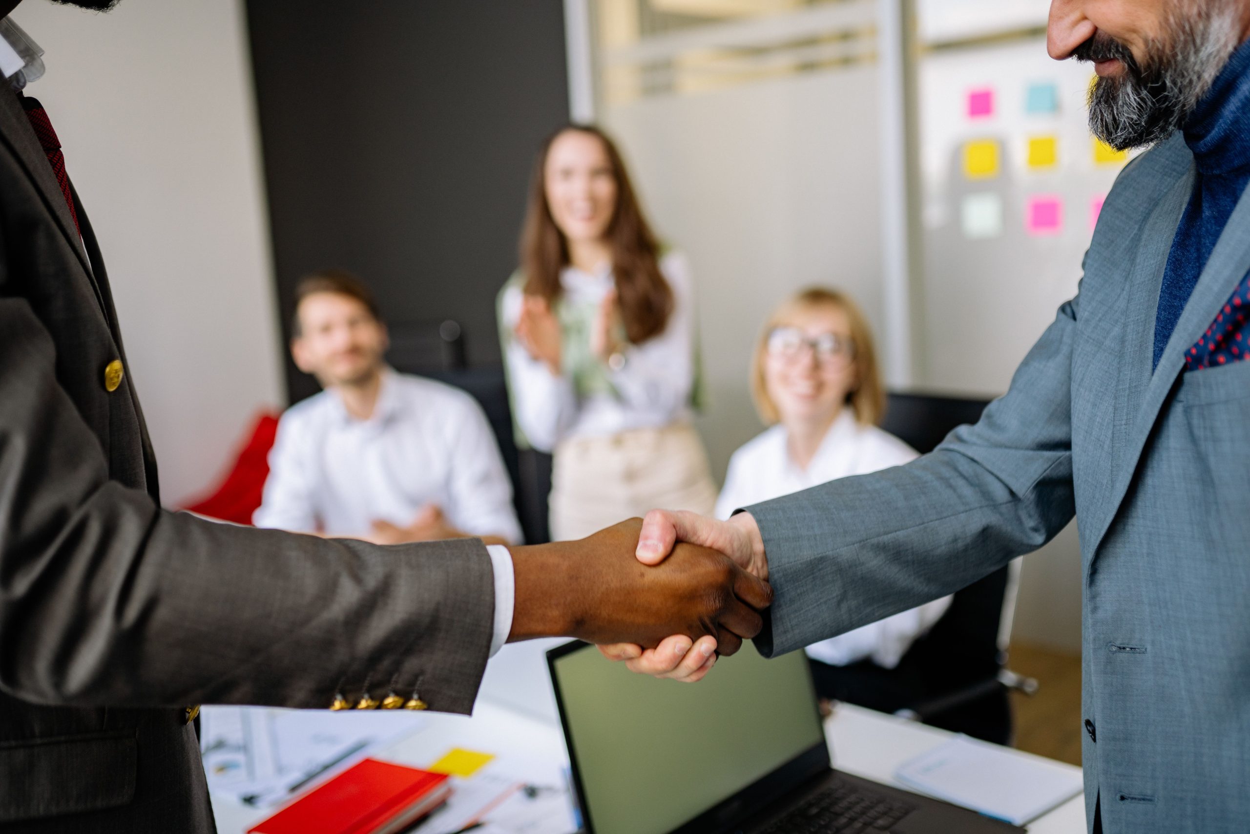 Close-up of a handshake between colleagues in a professional office setting, symbolizing a strong first impression at work.