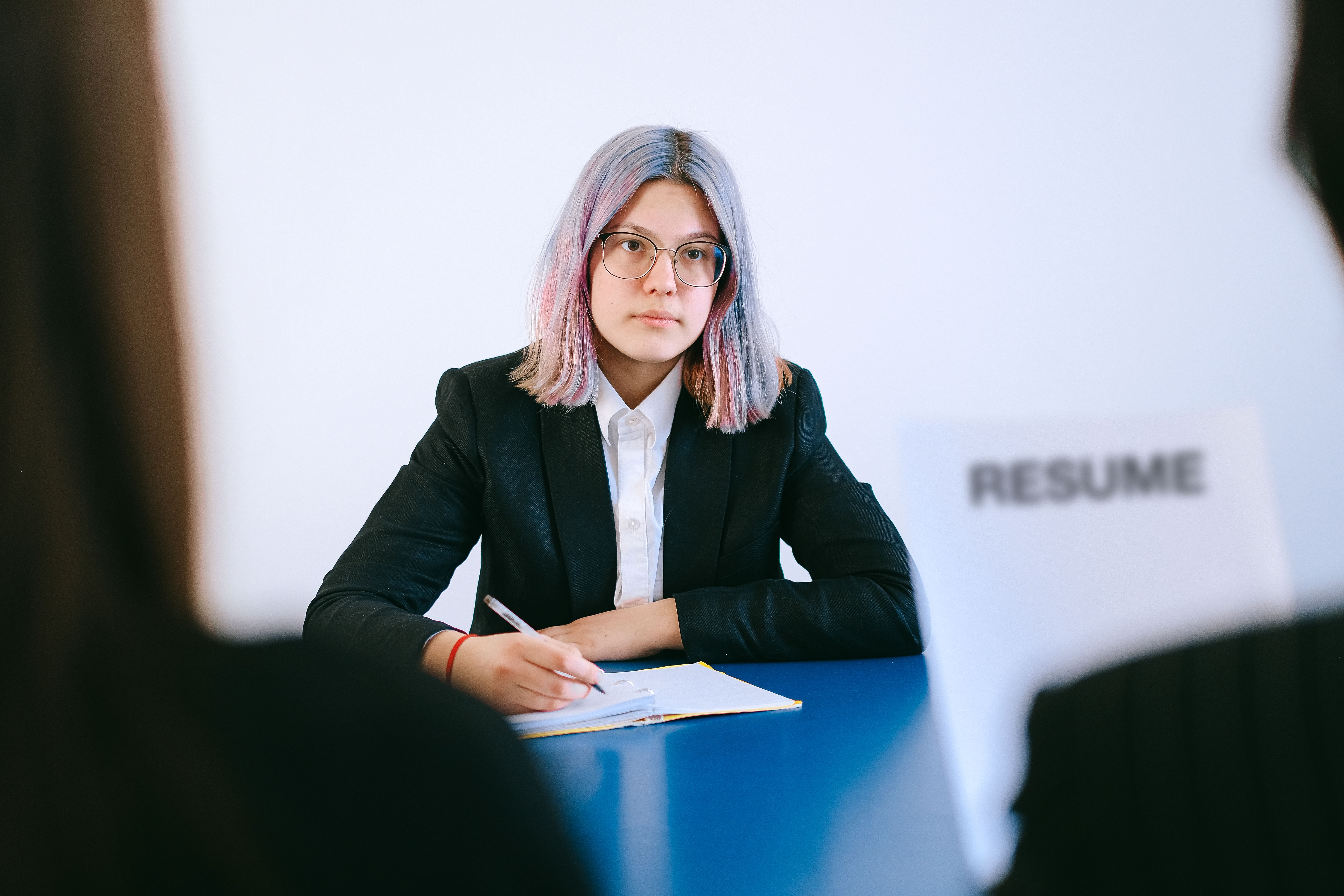 Young woman in a suit during a job interview writing notes on an application.